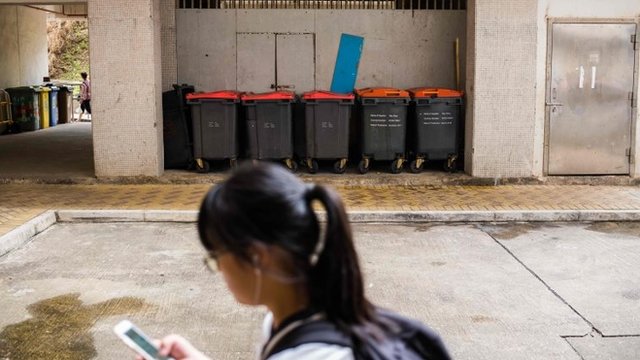 Una joven pasa ante los contenedores de basura a las afueras de la vivienda del hombre contagiado.