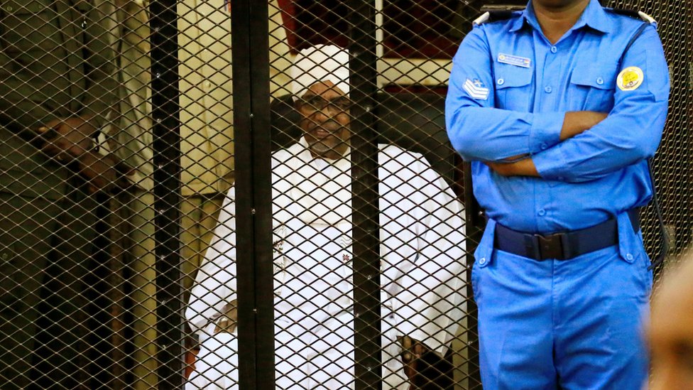 Бывший президент Судана Омар аль-Башир сидит в клетке во время вынесения приговора
