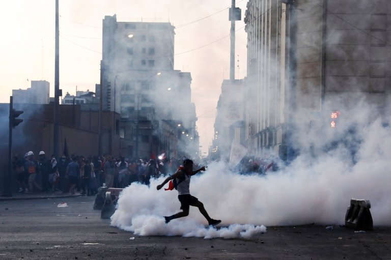 Un hombre corre entre el gas lanzado por la Policía en Lima.