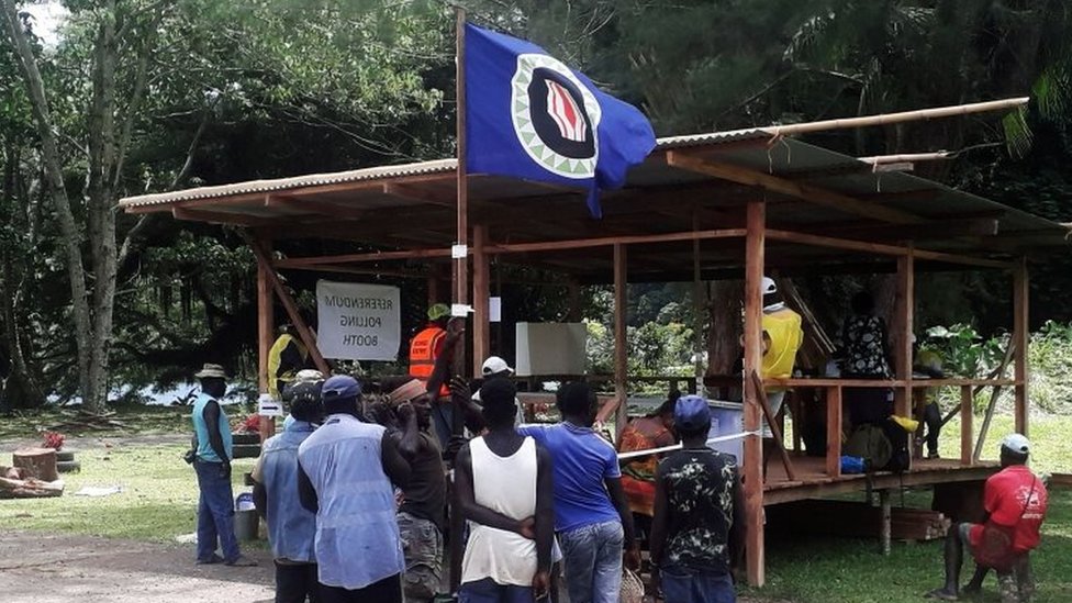 Избиратели держат флаг Бугенвиля на избирательном участке
