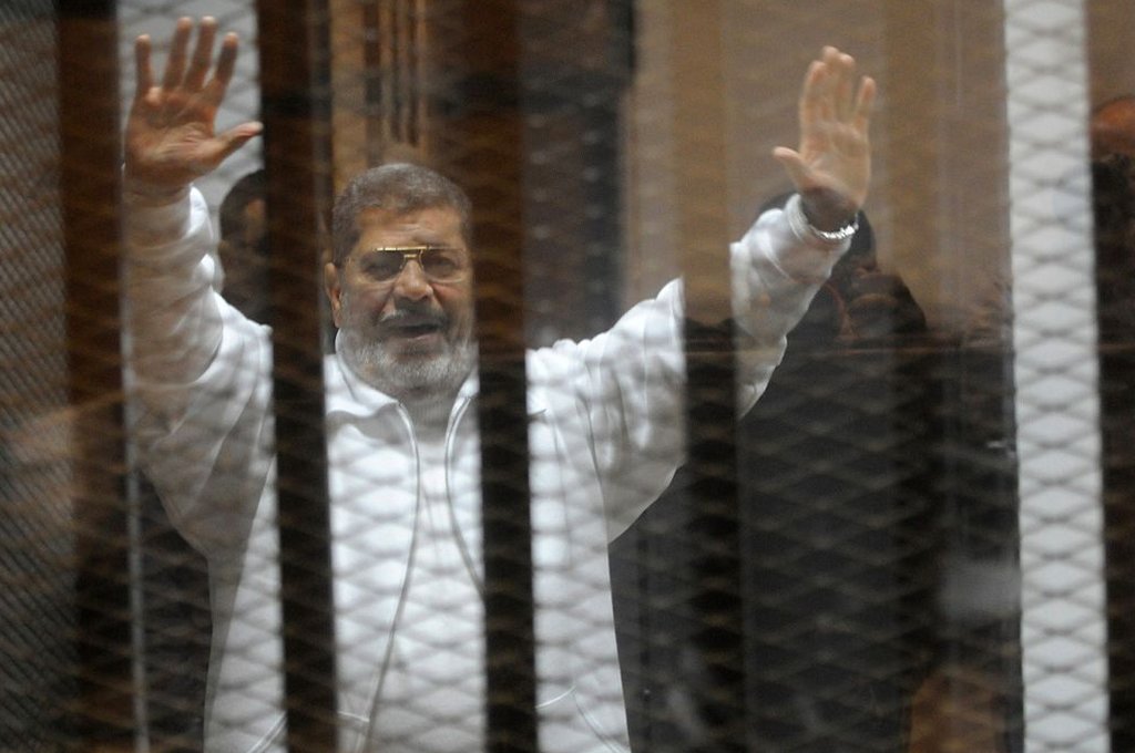 محمد مرسي يرفع يديه في قفص الاتهام.