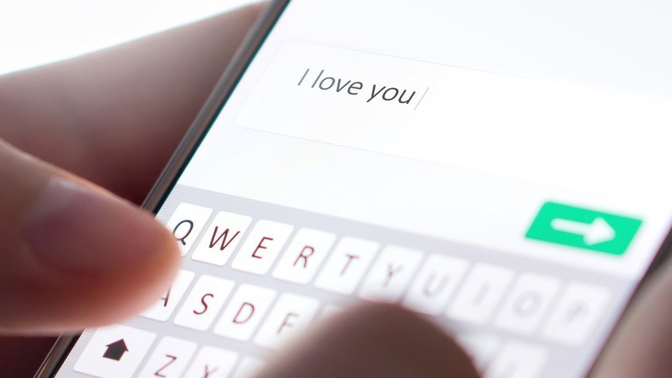 Una mujer tipeando "Te amo" en su celular