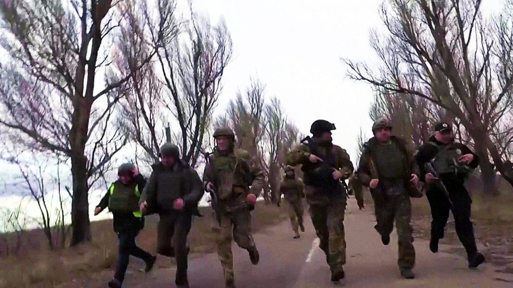 Ukrainian officials run from apparent shelling