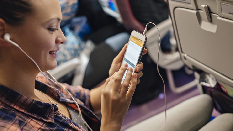Una mujer maneja su celular dentro de un avión.