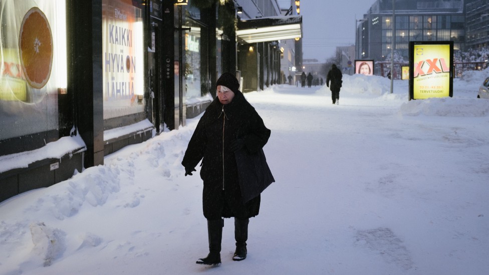 Mujer caminando en una calle cubierta de nieve en Helsinki