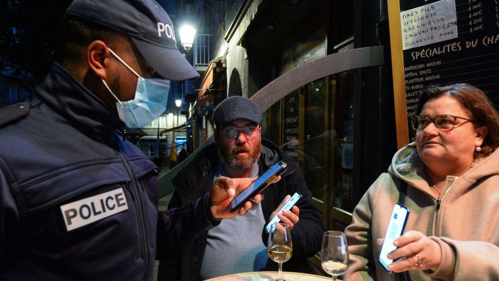 Un policía inspecciona los pases de covid de los clientes en un bar de Francia