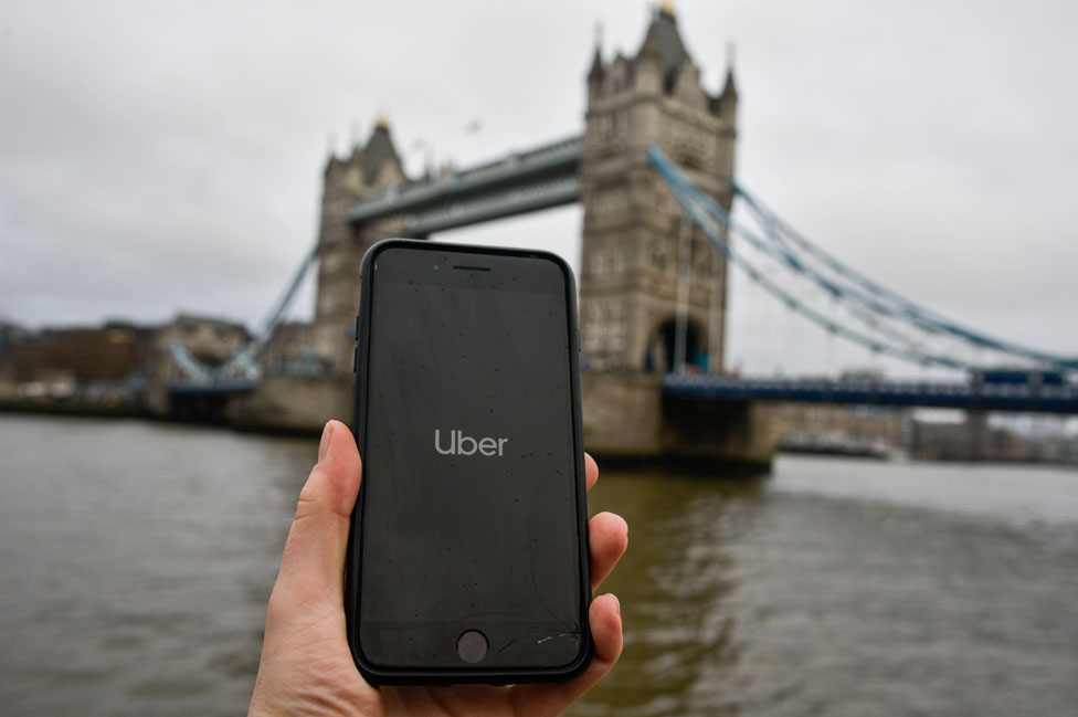 Un teléfono que muestra la aplicación Uber frente a Tower Bridge, en Londres