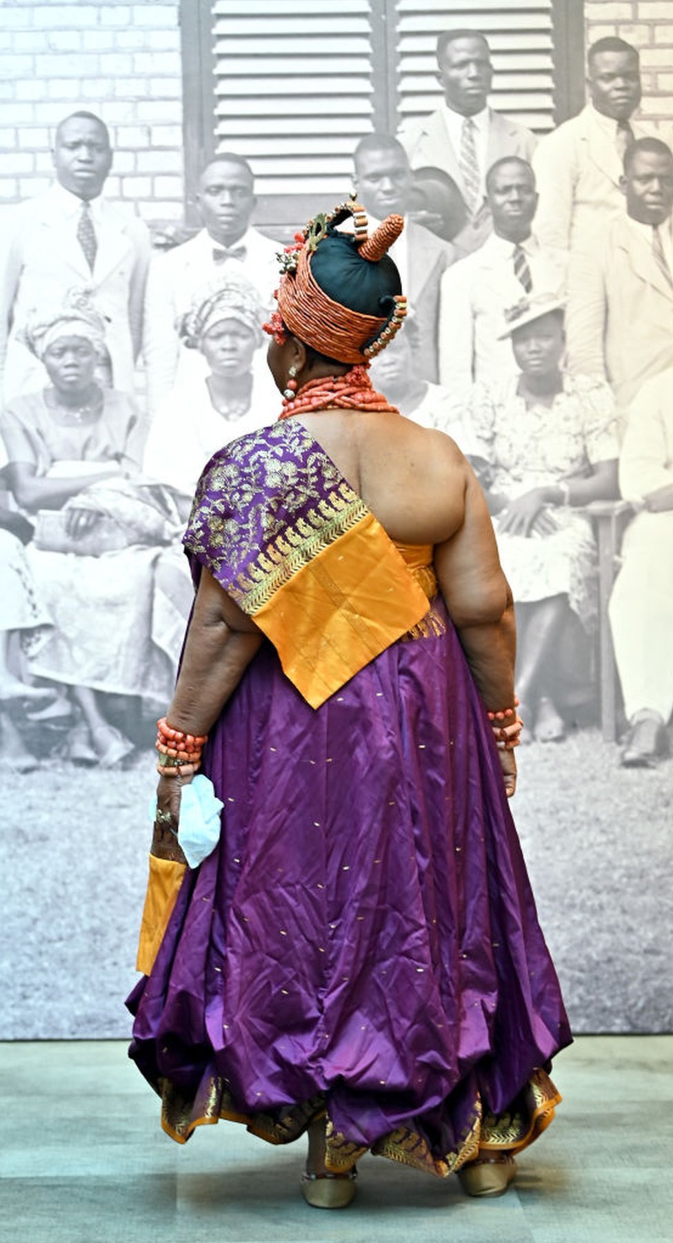 امرأة ترتدي ملابس أفريقية تقليدية تنظر إلى صورة كبيرة بالأبيض والأسود