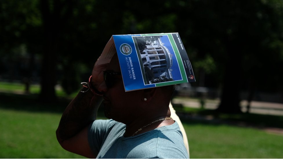 Турист использует путеводитель, чтобы прикрыть голову