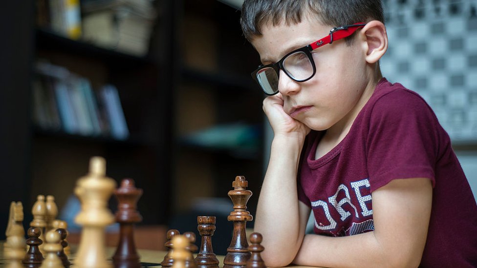 Niño frente a un tablero de ajedrez.