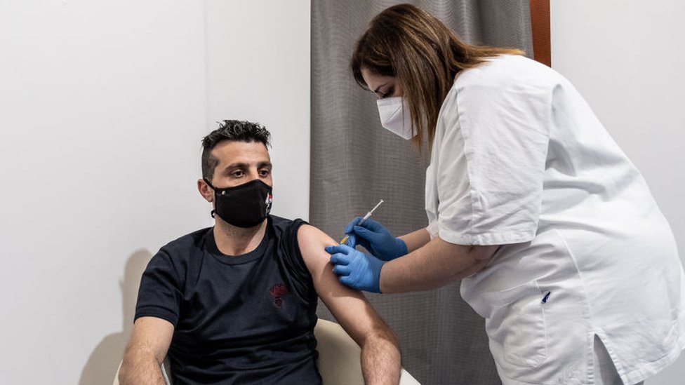 Una enfermera vacuna a un hombre joven en Italia.
