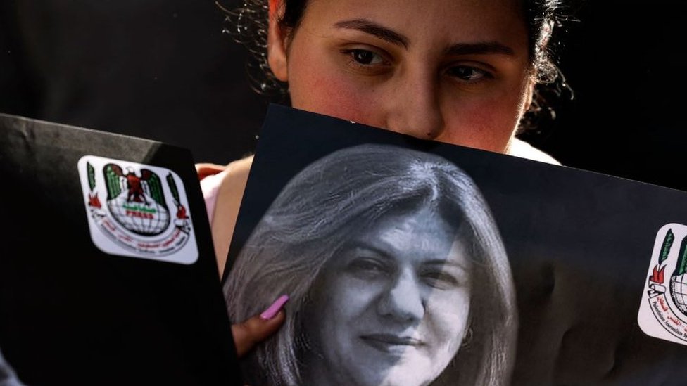 Seorang warga Palestina memegang foto Shireen Abu Aqla saat jenazahnya dibawa ke kantor Al Jazeera di Ramallah.