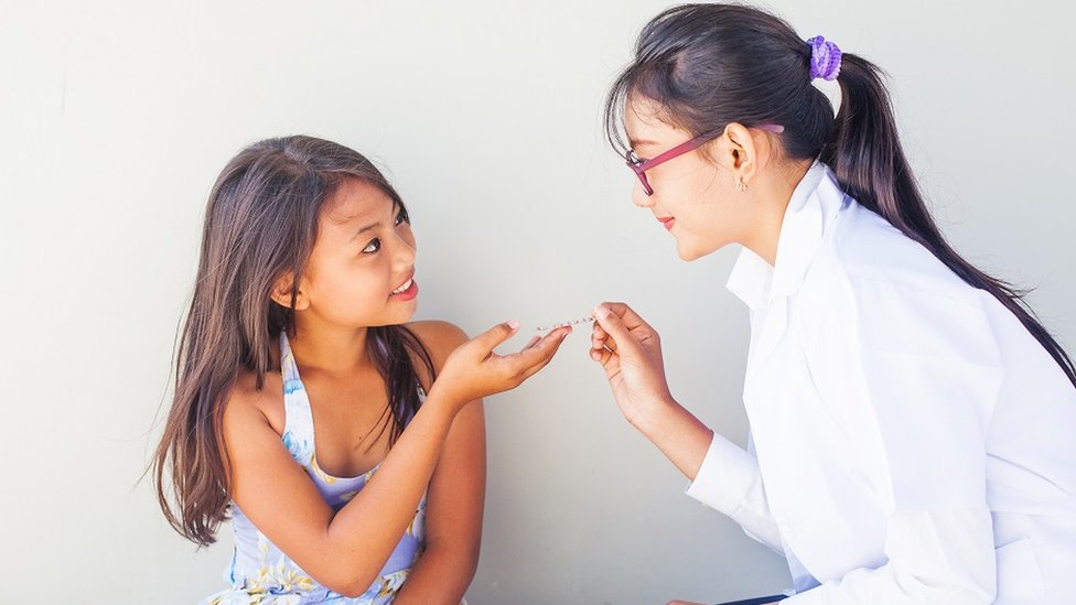 Una doctora le da medicina a una niña.