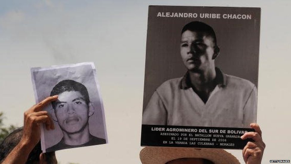 Люди держат фотографии убитых родственников во время марша против ложных срабатываний 6 марта 2009 года в Боготе.