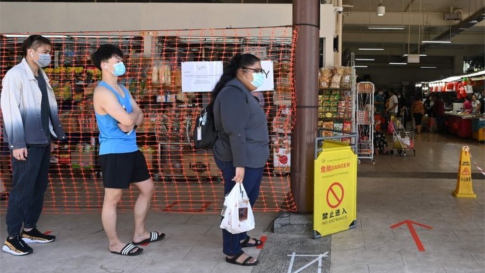 Personas hacen fila para entrar a una tienda en Singapur