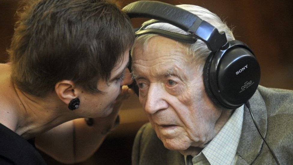 Sandor Kepiro (R) is welcomed by his psychologist Anna Szoor (L) as he sits in a wheelchair at Budapest Municipal Court on June 24, 2011