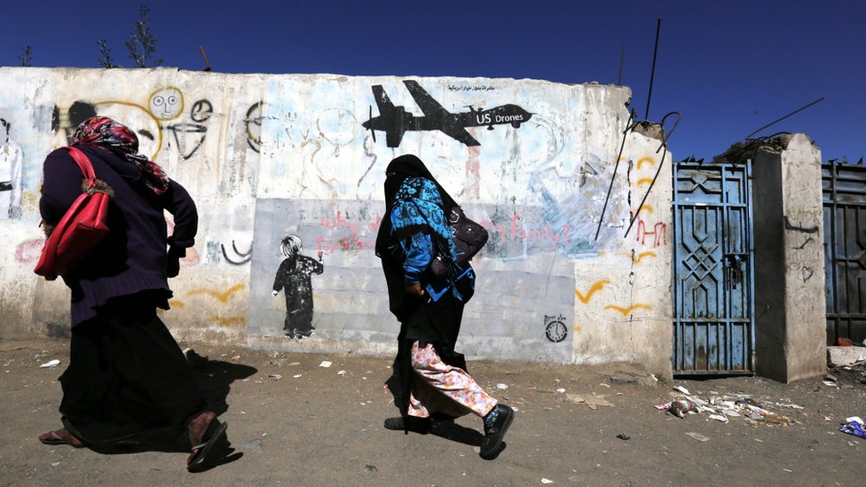 Йеменские женщины проходят мимо граффити в знак протеста против ударов американских дронов о стену в Сане, Йемен (24 декабря 2016 г.)