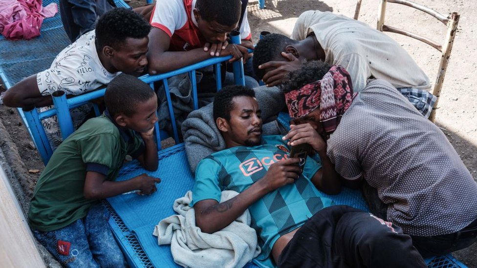 Эфиопские беженцы собираются вокруг чьего-то телефона в Хамдаете, Судан - 8 декабря 2020 г.