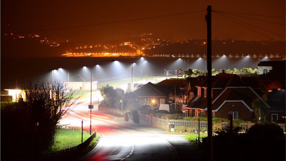 Postes de luz iluminando una carretera.