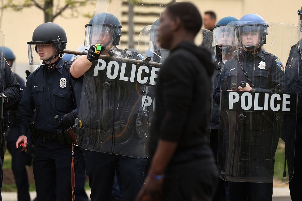 Policía apunta a un hombre negro con un arma Taser.