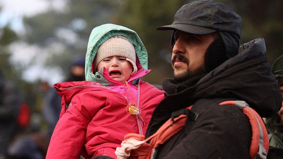 Un hombre carga a un niño en la frontera de Bielorrusia y Polonia