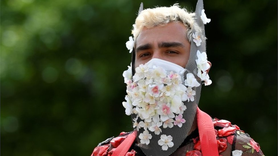 Участник надевает маску, украшенную цветами, на митинге Black Trans Lives Matter в Лондоне