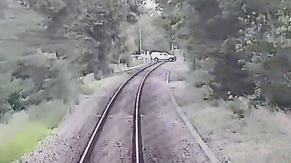 На кадрах с видеонаблюдения с поезда в Великой Англии видно, что на небольшом расстоянии впереди дорогу пересекает автомобиль