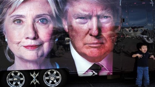A boy gestures next to a backdrop of US Democratic presidential nominee Hillary Clinton and her Republican counterpart Donald Trump at the Hofstra University, in Hempstead, New York