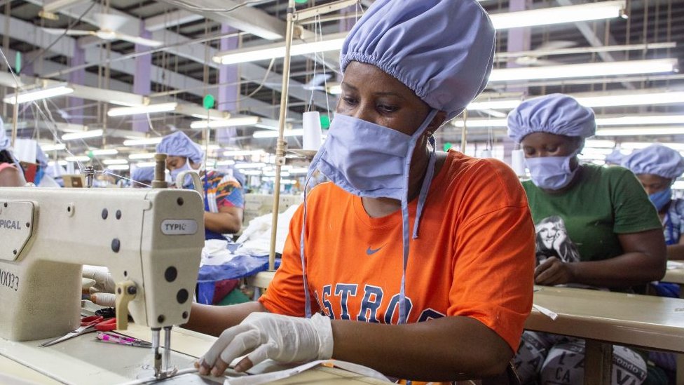 Женщина шьет маску на фабрике