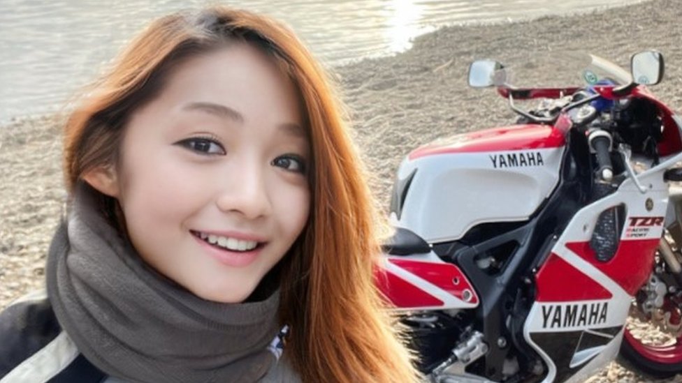 Foto de una mujer joven con su motocicleta en Twitter: @azusagakuyuki