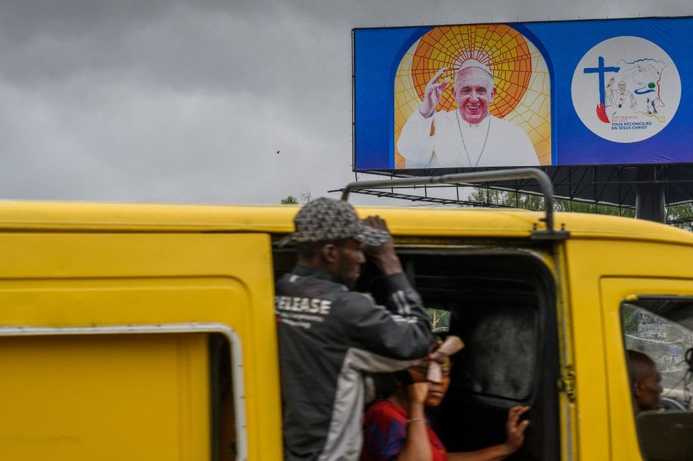 عربة تمر من أمام لوحة عليها صورة البابا فرانسيس الأحد في كينشاسا، عاصمة جمهورية الكونغو الديمقراطيبة.