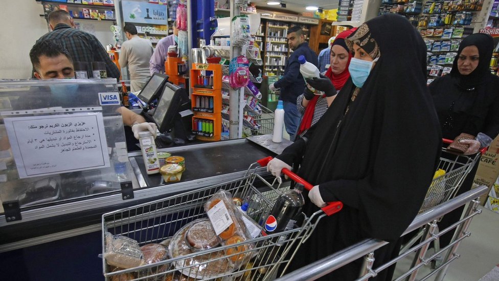 Женщина ждет у кассы супермаркета в Багдаде перед началом комендантского часа