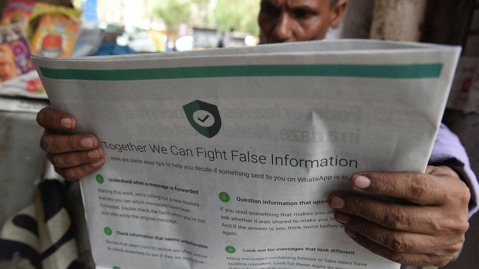 На этой фотографии изображен индийский продавец газет, читающий газету с рекламой WhatsApp на последней странице, предназначенной для противодействия фальшивой информации, в Нью-Дели 10 июля 2018 г.