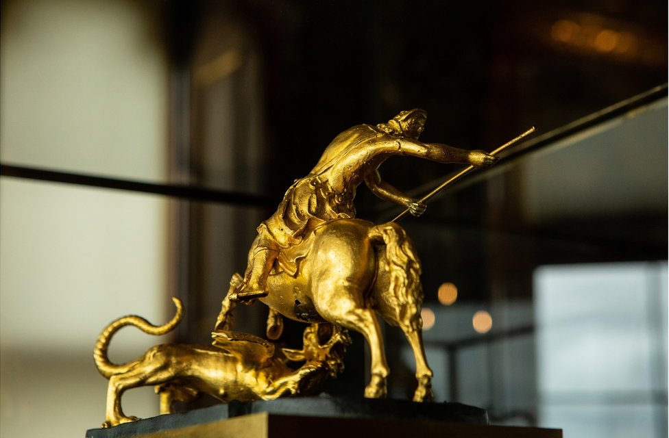 A close-up of a small gold statue of St George and the Dragon