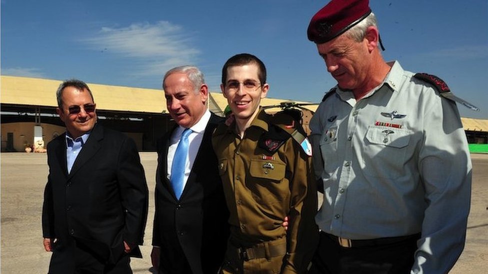 In this handout photo provided by the Israeli Defense Force, freed Israeli soldier Gilad Shalit (2nd R) walks with Defence Minister Ehud Barak (L), Israeli Prime Minister Benjamin Netanyahu (2nd, L) and IDF Chief of General Staff Benny Gantz (R) at Tel Nof Airbase on 18 October 2011 in central Israel
