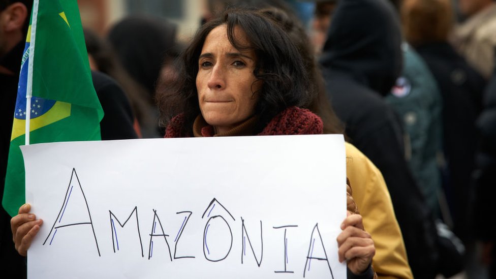 Mujer llevando una pancarta que dice Amazonas.