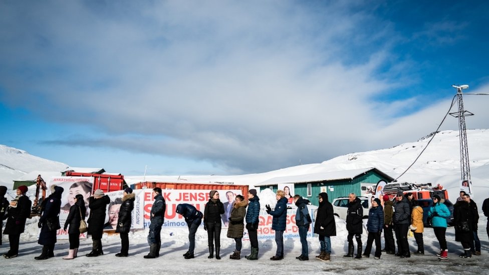 Voters stand in line waiting to cast their votes during the parliamentary election, outside the Inussivik arena, in Nuuk, Greenland