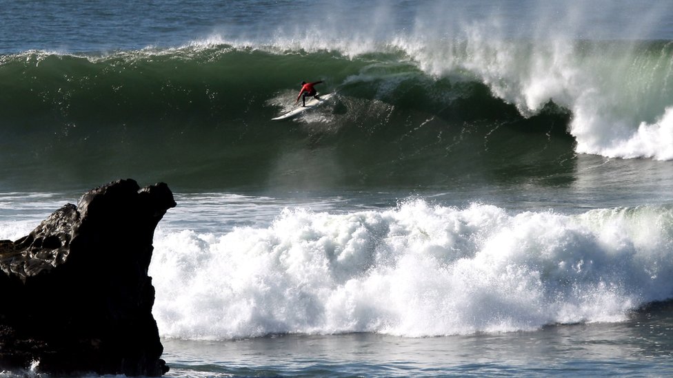 Las temibles rocas de Mavericks recuerdan constantemente el peligro al que están expuestos los surfistas de olas grandes. Surfista hombre en el torneo por invitación de Mavricks