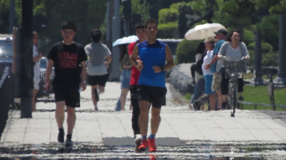 Эффекты теплового тумана видны, когда пешеходы идут по улице во время сильной жары в Токио 2 августа 2018 г.