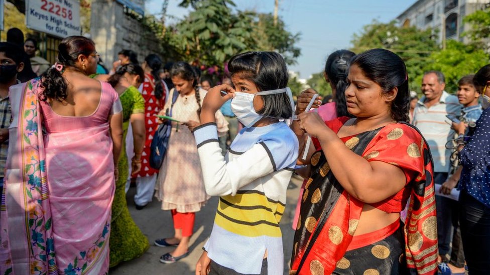 Мать надевает маску на свою дочь из-за опасений по поводу распространения коронавируса COVID-19, когда она посещает первый день экзаменов в десятом классе в Секундерабаде, городе-побратиме Хайдарабада, 19 марта 2020 года.