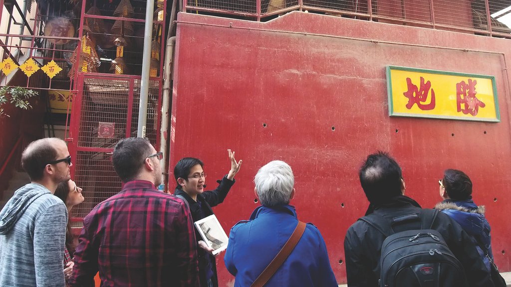 Paul Chan showing a group of tourists a sight with cultural and historic significance on a walking tour in 2014.