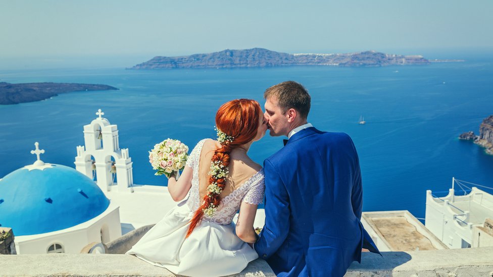 Wedding couple sitting and watching the sea next to a church