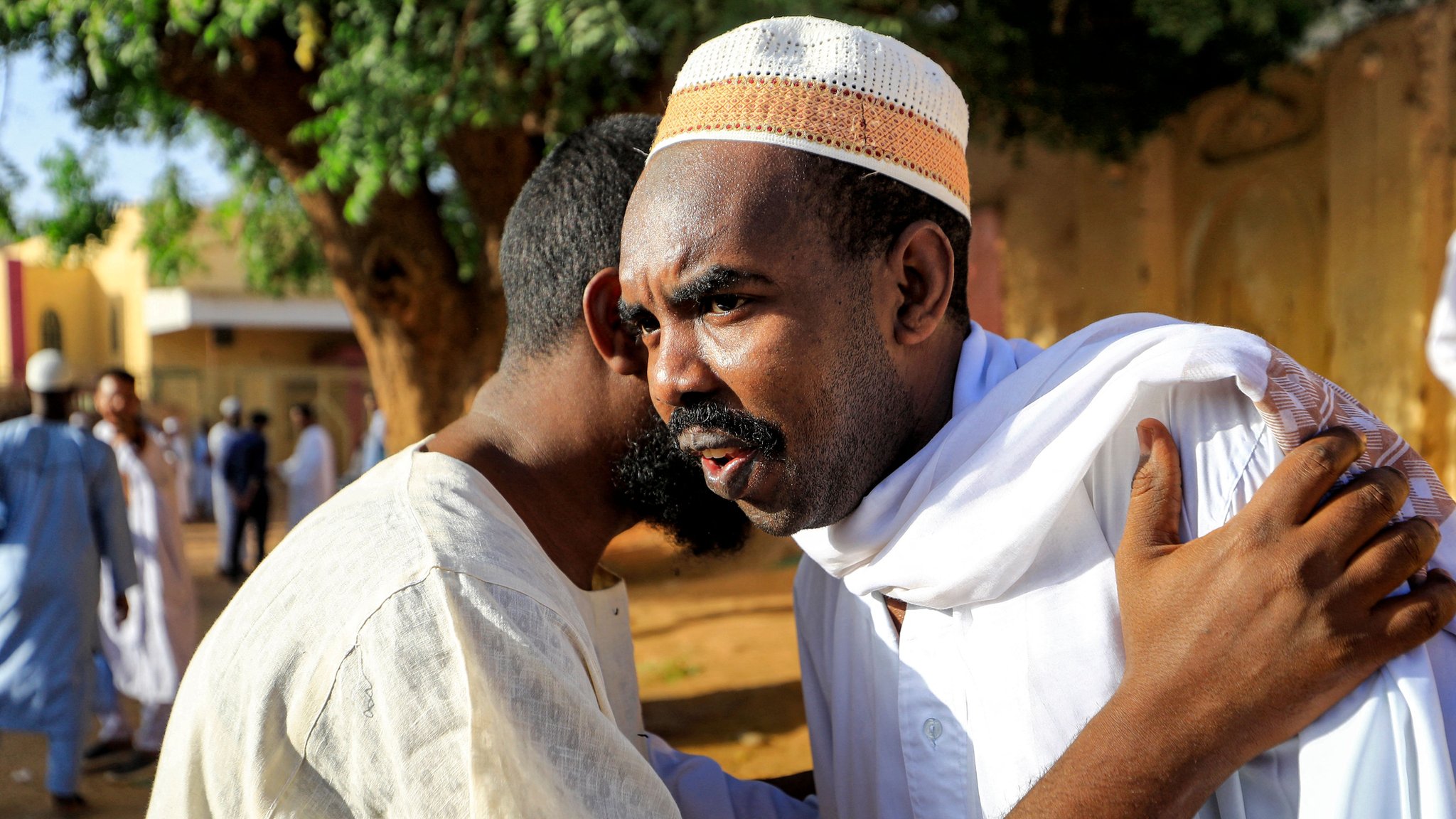 اشتباكات السودان: كيف تحولت وسوم تهنئة بالعيد إلى مناشدات لطلب العون؟ 2 رجلان سودانيان يتعانقان بعد صلاة العيد