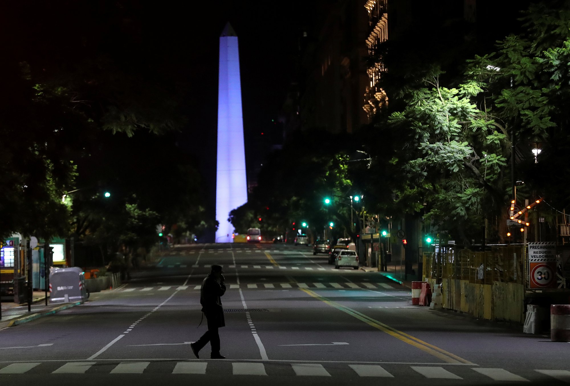 Una persona en una avenida solitaria de Buenos Aires con el Obelisco en el fondo