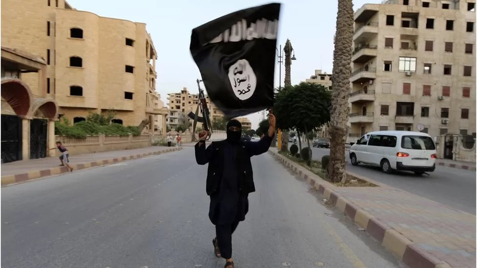 أحد أعضاء تنظيم الدولة الإسلامية في سوريا يلوح بعلم التنظيم عام