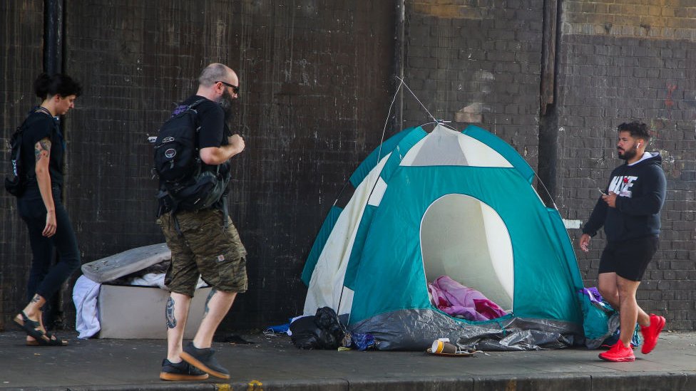 Люди проходят мимо палатки бездомного в Лондоне в сентябре
