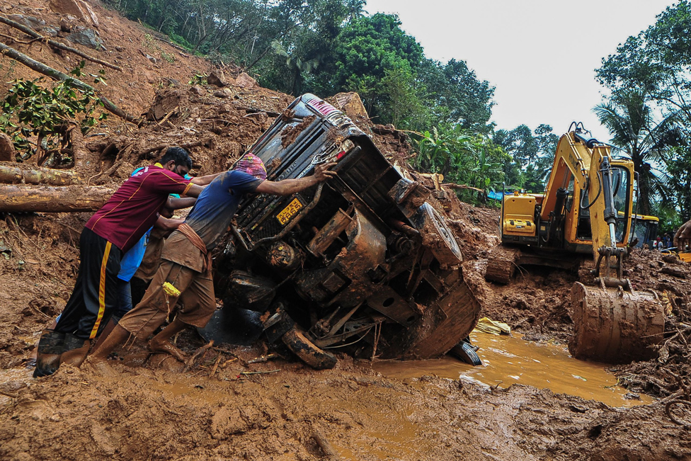 عمال الإنقاذ يدفعون عربة مقلوبة في موقع انهيار أرضي في كوكايار