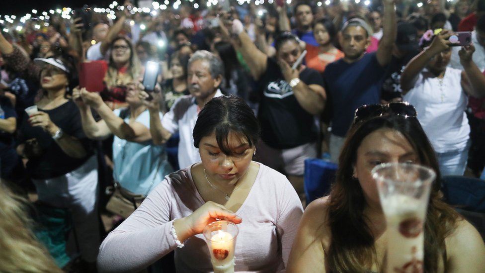 Люди держат свои телефоны вместо свечей на межконфессиональной акции памяти жертв массового расстрела