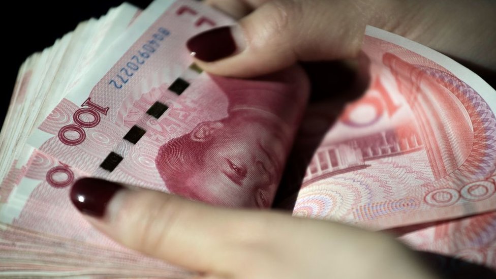 Manos sosteniendo varios billetes de yuanes.