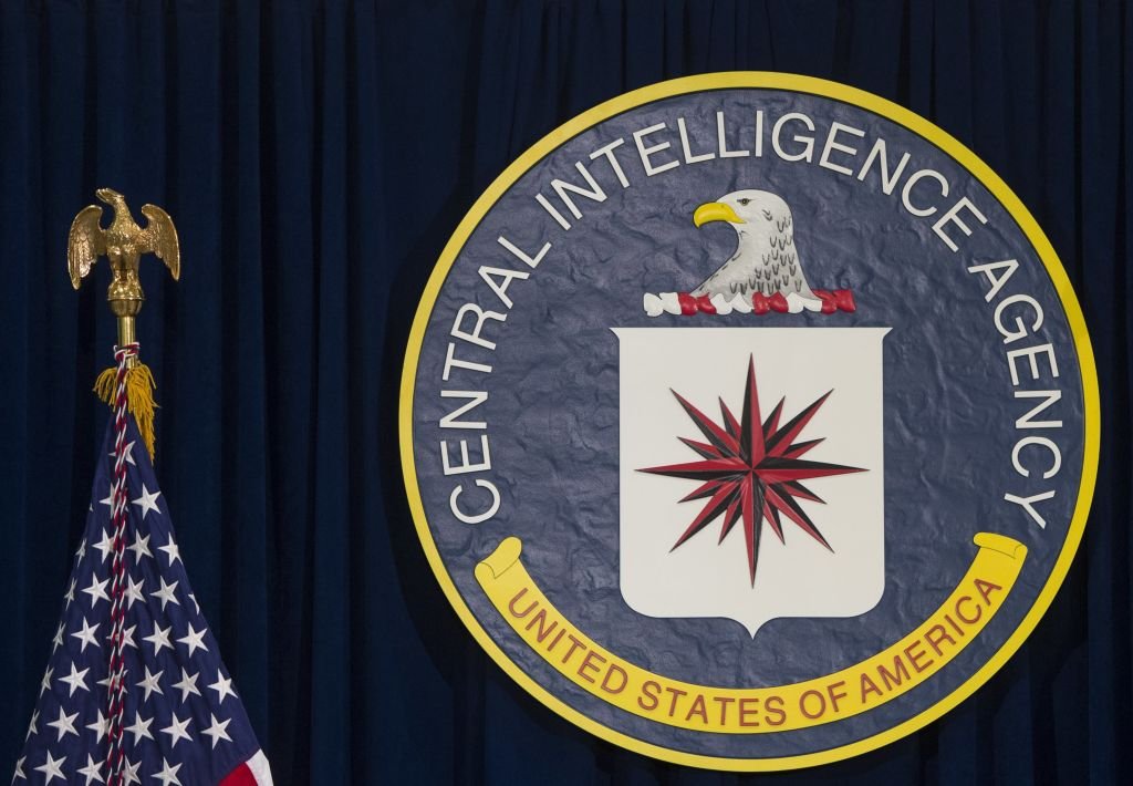 Escudo da CIA ao lado da bandeira dos Estados Unidos